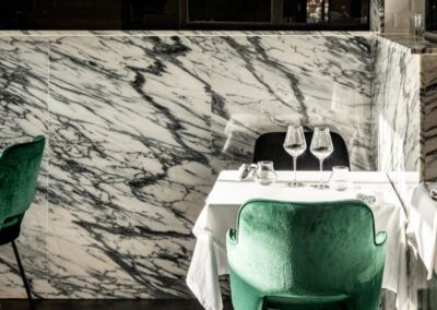 Tables intérieures LVR avec mur en marbre et chaises en velour vert