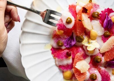 Assiettes blanche LVR à base d'agrumes, avec fleurs comestibles, radis colorés, pamplemousse.