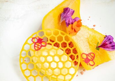 Dessert à la poire, glace à la vanille, fleurs comestibles et croquant en forme d'alvéoles d'abeilles